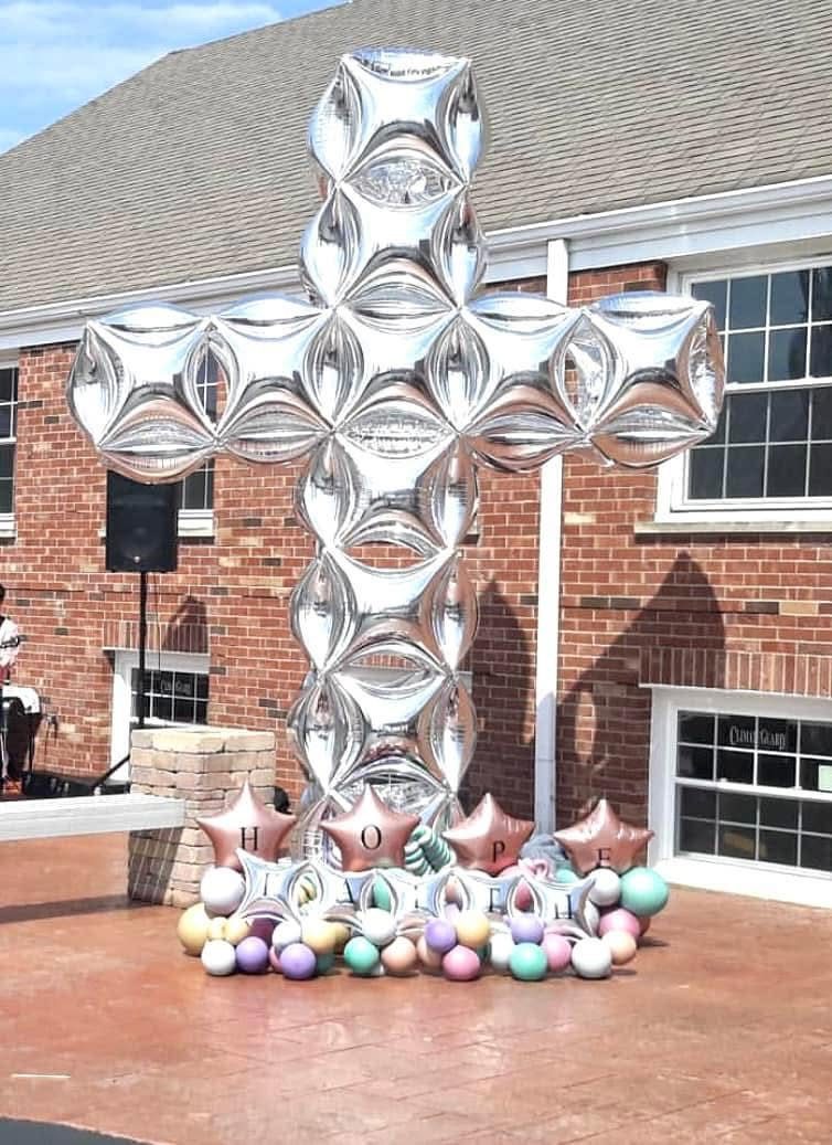 Large silver foil balloon cross installation outdoors