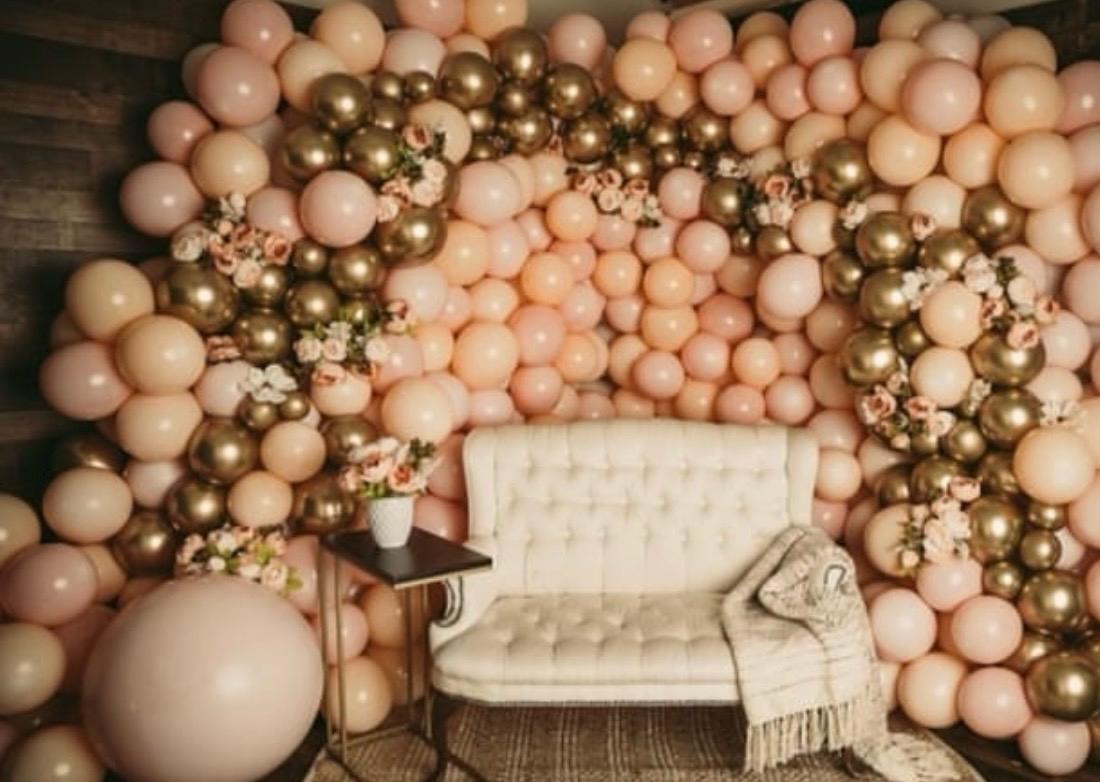 Blush and gold balloon wall with an elegant lounge seat