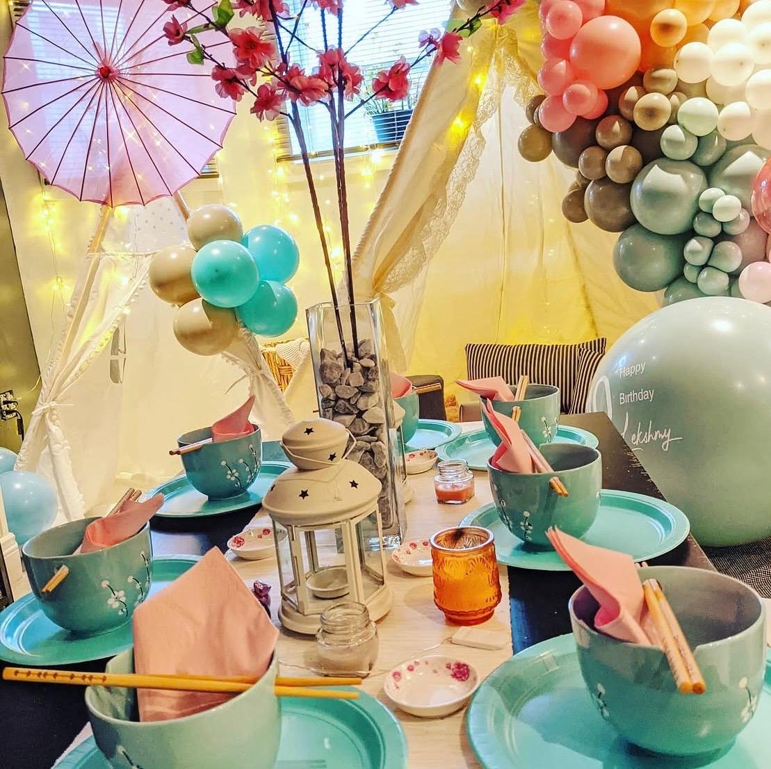 Pastel party table framed by a colorful balloon garland