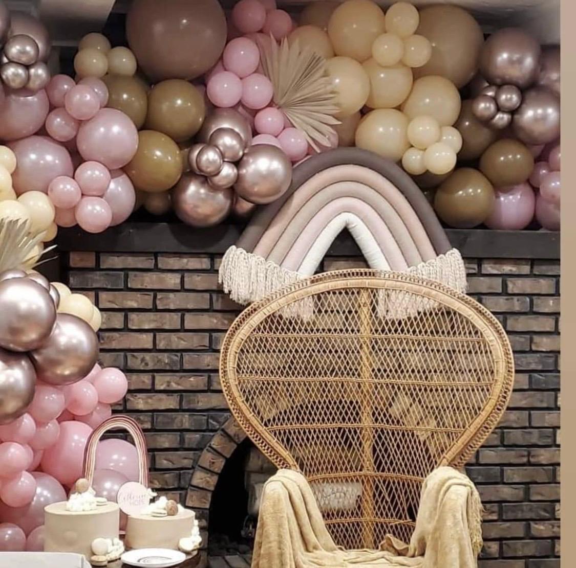 Neutral rainbow balloon wall with a woven statement chair